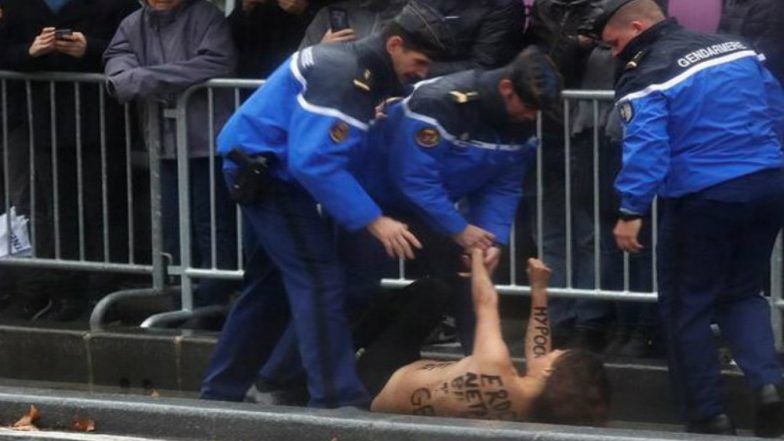 Police stop topless protesters approaching Trump motorcade in Paris