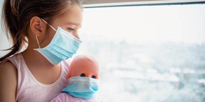 covid-19 in childrenLittle girl with doll wearing a protective mask. Copy space. Sad